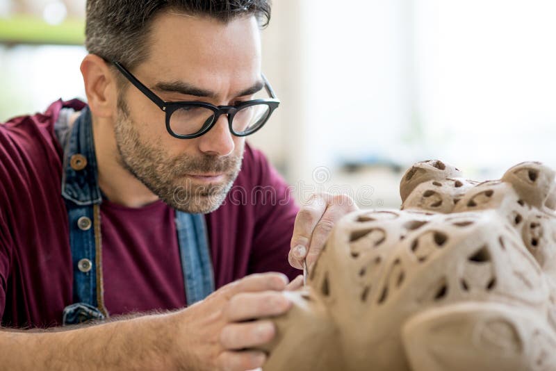 Ceramist Dressed in an Apron Sculpting Statue from Raw Clay in Bright Ceramic Workshop. stock photos Ceramist Dressed in an Apron Sculpting Statue from Raw Clay in Bright Ceramic Workshop. stock photos
