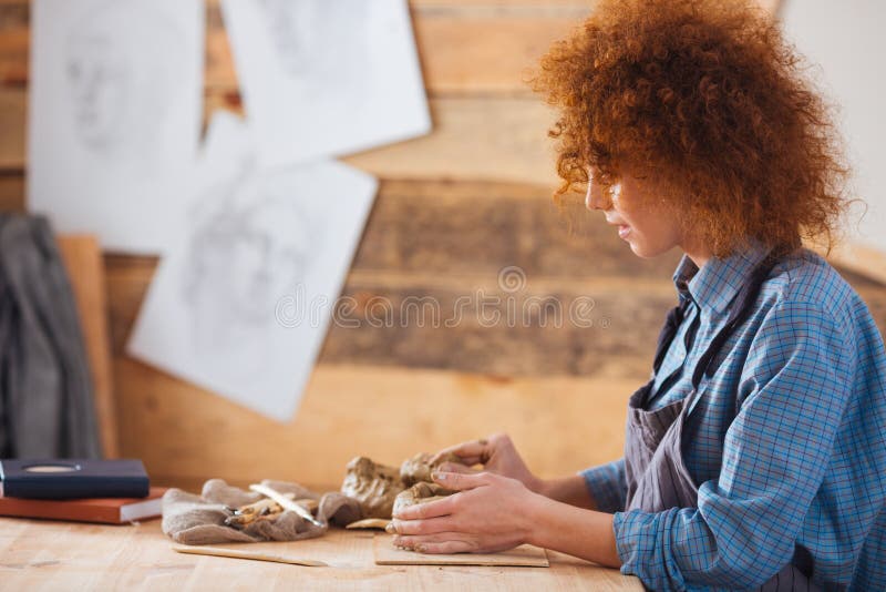 Ceramist focalisé de femme créant la sculpture utilisant l'argile dans l'atelier de poterie images stock Ceramist focalisé de femme créant la sculpture utilisant l'argile dans l'atelier de poterie images stock