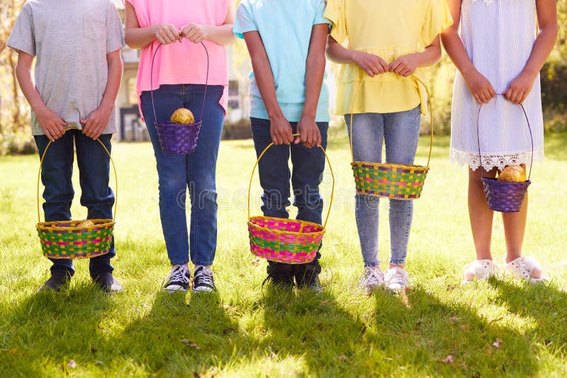 Cerca de cinco niños con cestas en caza de huevos en el jardín fotografía de archivo libre de regalías