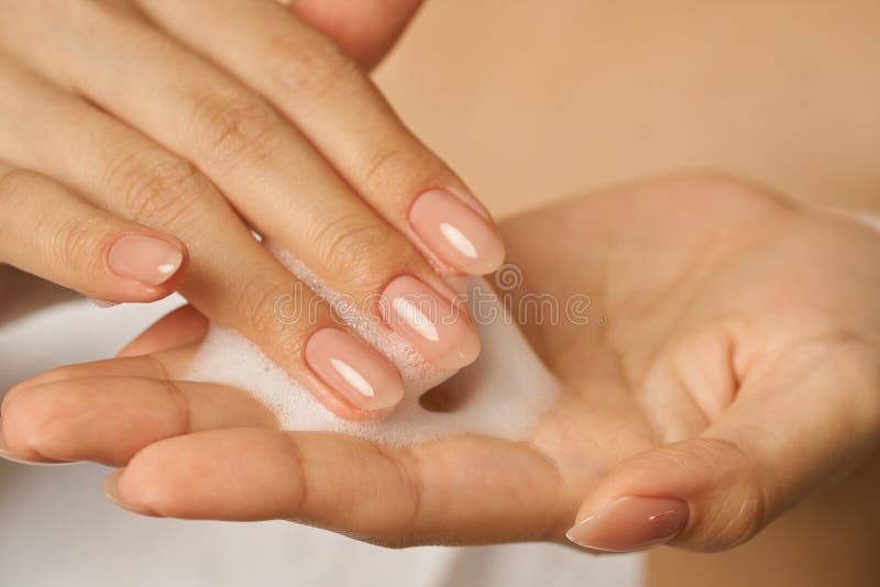 Cerca de las manos femeninas que celebra la aplicación de la limpieza facial de espuma suave