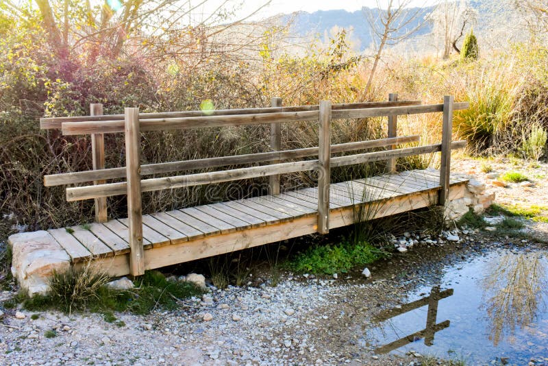 cercano para arriba de un puente de madera en un un montón del río de hierbas y de precipitaciones en la luz soleada de la salida imagenes de archivo cercano para arriba de un puente de madera en un un montón del río de hierbas y de precipitaciones en la luz soleada de la salida imagenes de archivo