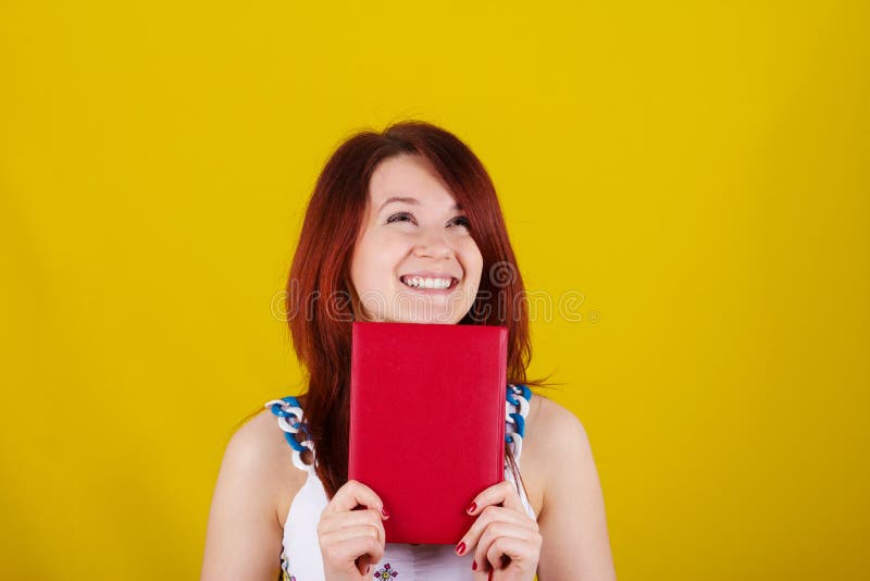 Cercare giovane studente sorridente, ragazza della donna che tiene un libro rosso immagine stock libera da diritti Cercare giovane studente sorridente, ragazza della donna che tiene un libro rosso immagine stock libera da diritti