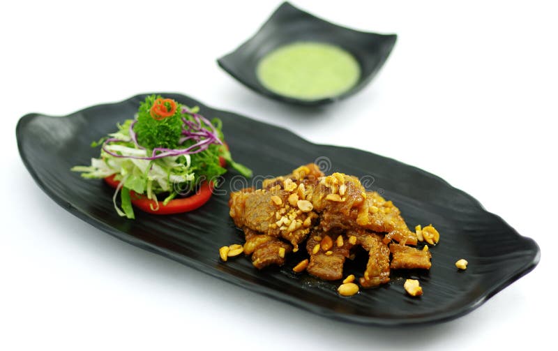 Cerdo cocido con la salsa y la ensalada de chile en el disco negro imagen de archivo libre de regalías Cerdo cocido con la salsa y la ensalada de chile en el disco negro imagen de archivo libre de regalías