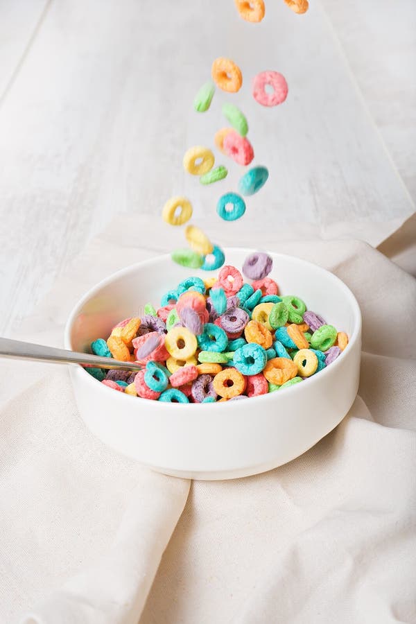 Cereal colorido que cae en un cuenco en un fondo blanco