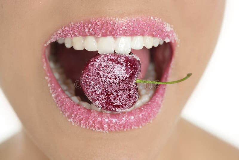 Cereza con sugra entre los dientes de la mujer imágenes de archivo libres de regalías Cereza con sugra entre los dientes de la mujer imágenes de archivo libres de regalías