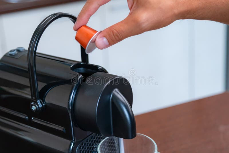 Cerrar de la mano insertar una cápsula en una máquina de café en casa. concepto de descanso para el café.