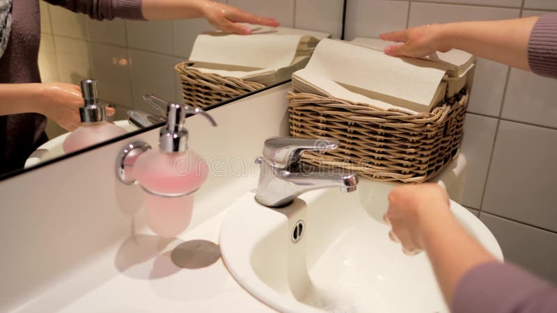 Cerrar la mano femenina en el cuarto de baño lavar las manos bajo el agua corriente en el concepto de lavabo de cerámica blanca de