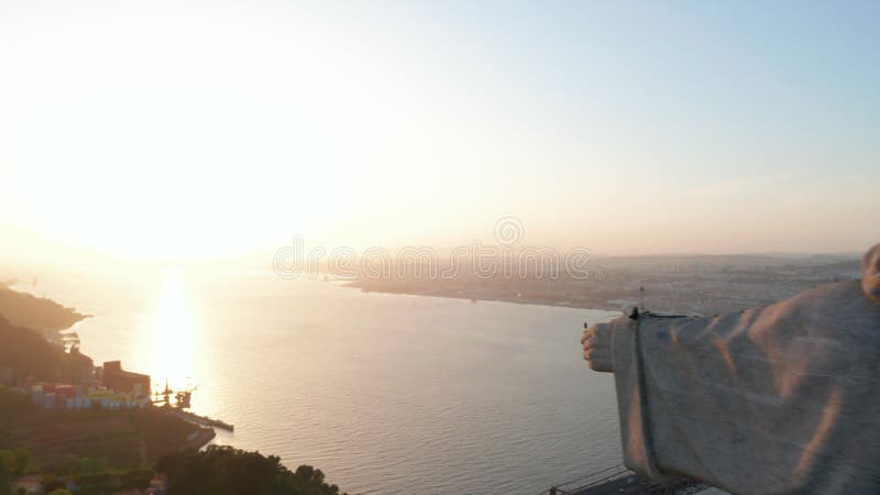 Cerrar la órbita aérea del santuario de cristo el rey estatua en la colina con revelación de ponte 25 de abril puente rojo en almacen de video