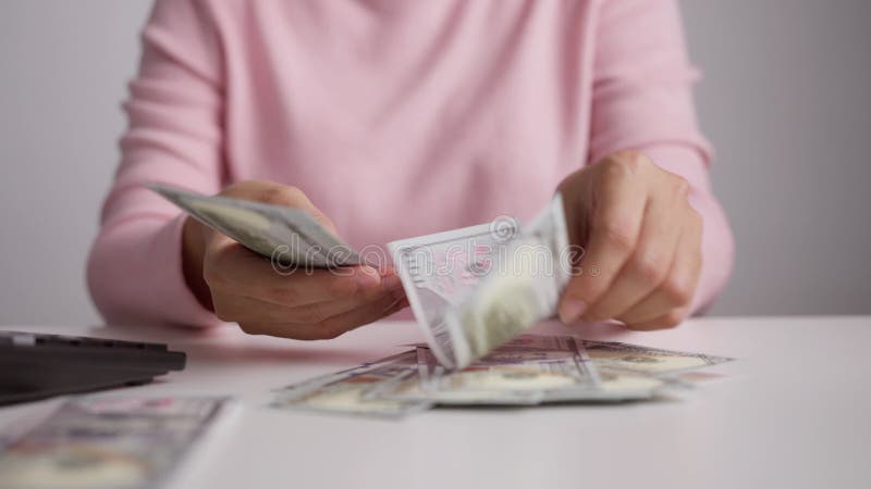 Cerrar las manos de la mujer contando los billetes de dólares