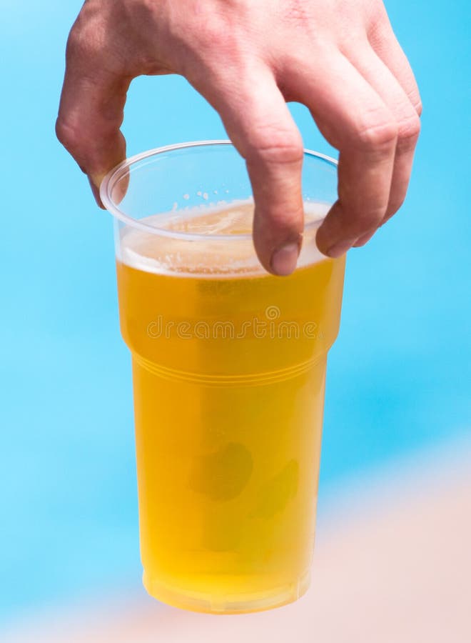 Cerveja fresca em um copo plástico na mão imagens de stock Cerveja fresca em um copo plástico na mão imagens de stock