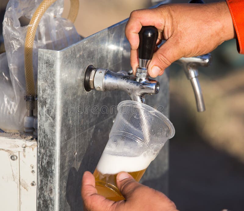 Cerveja fresca em um copo plástico na mão imagem de stock Cerveja fresca em um copo plástico na mão imagem de stock