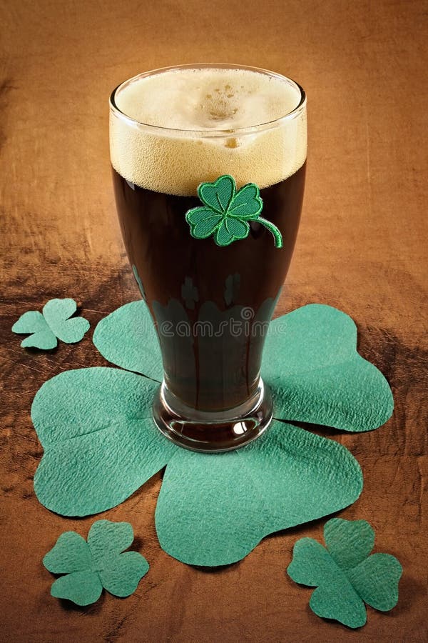 Dark Irish beer for St Patick's Day on napkins stylized under clover leaf. Dark Irish beer for St Patick's Day on napkins stylized under clover leaf