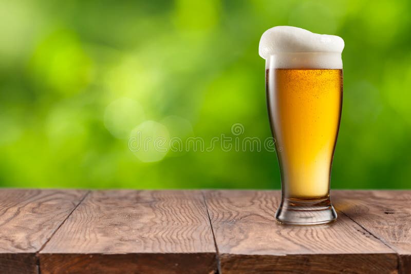 Cerveja no vidro na tabela de madeira contra o verde imagens de stock royalty free Cerveja no vidro na tabela de madeira contra o verde imagens de stock royalty free