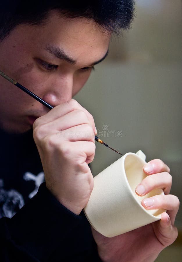 A Japanese man painting a design onto Satsuma ware pottery. A Japanese man painting a design onto Satsuma ware pottery.