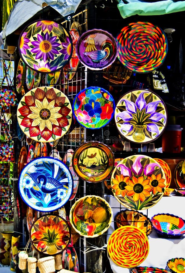 Brightly painted colorful ceramic plates hang on a stall in a crafts market in Costa Maya, Mexico, a tourist destination on the Caribbean Sea. Brightly painted colorful ceramic plates hang on a stall in a crafts market in Costa Maya, Mexico, a tourist destination on the Caribbean Sea.