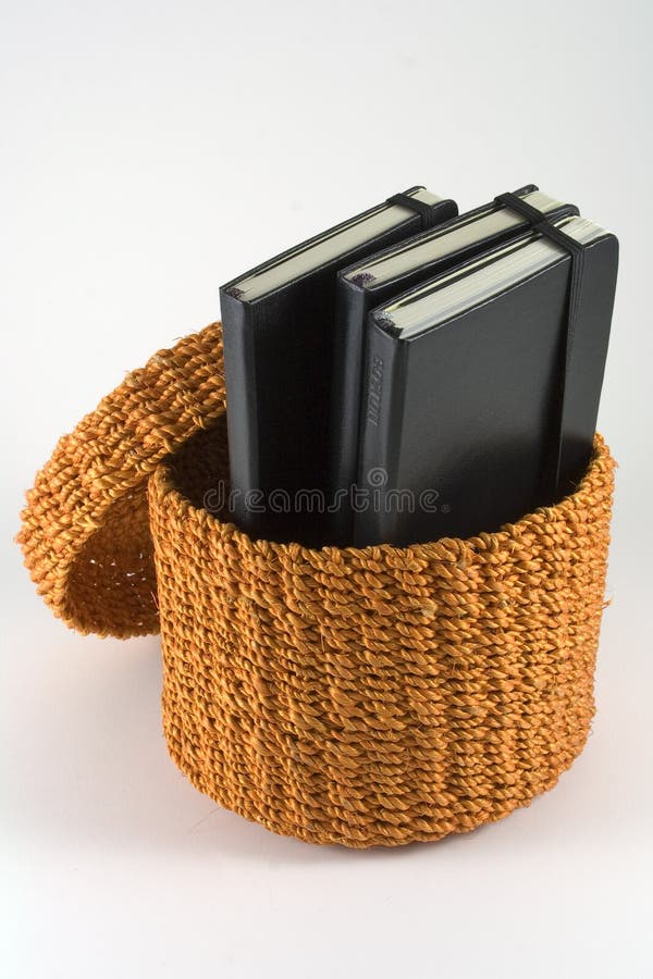 Cesta alaranjada do rattan com cadernos imagem de stock Cesta alaranjada do rattan com cadernos imagem de stock