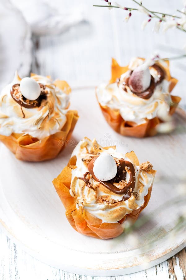 Cestas da pastelaria de Filo da P?scoa com merengue e chocolate e os ovos de chocolate derretidos em um fundo branco Espa?o para imagem de stock Cestas da pastelaria de Filo da P?scoa com merengue e chocolate e os ovos de chocolate derretidos em um fundo branco Espa?o para imagem de stock