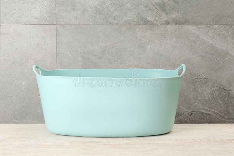 Cesto de roupa de plástico vazio próximo à parede cinzenta fotografia de stock