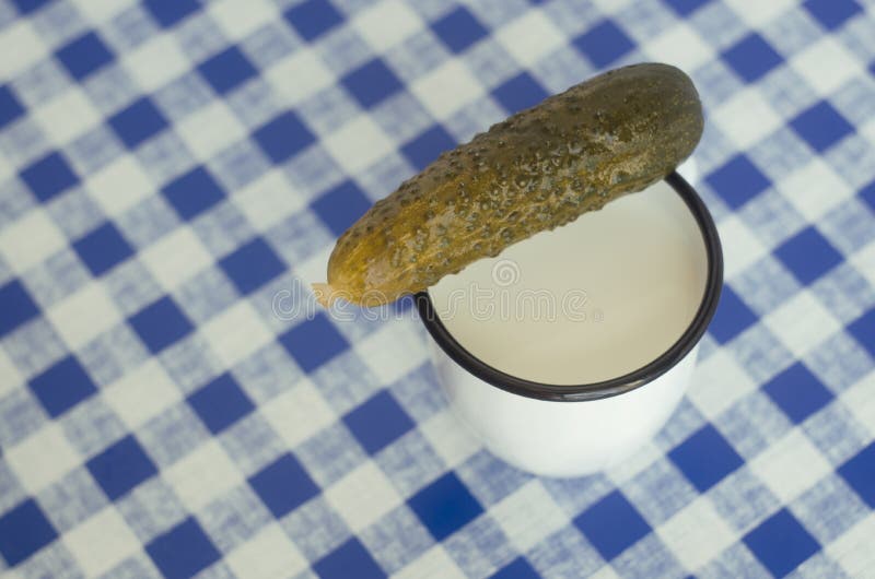 Salted cucumber and mug with milk on tartan tablecloth. Salted cucumber and mug with milk on tartan tablecloth