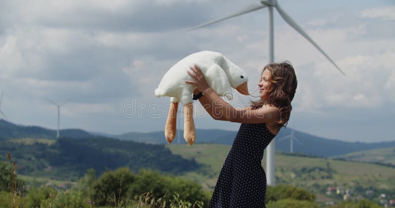 Cette vidéo pleine de chaleur capture une scène joyeuse d'une petite fille heureuse debout dans un champ avec des éoliennes images libres de droits