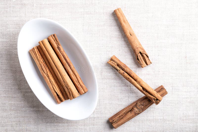 Ceylon cinnamon attacca le quaglie di cannella in una ciotola bianca ovale sul lino immagine stock libera da diritti