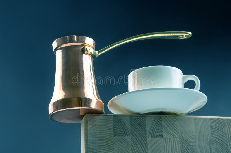 Cezve tradiționale din cupru, cu mâner de aur pereche cu o cupă albă și o farfurie pe o suprafață din lemn setată pe un gradient î royalty free stock photo