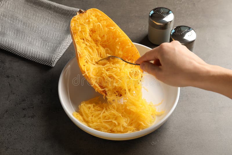Chair de éraflure de femme de courge de spaghetti cuite avec la fourchette à la table