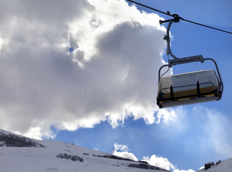 Chair-lift in ski resort and blue sky with sunlight clouds at sun evening