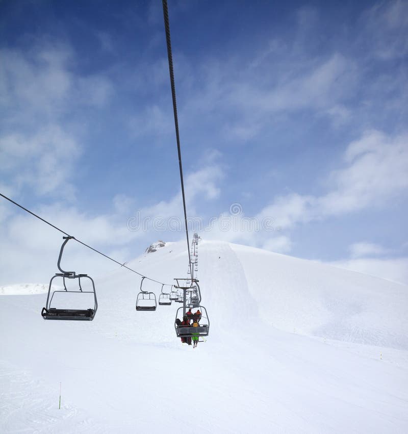Chair-lift, snow ski slope and cloudy sky with falling snow