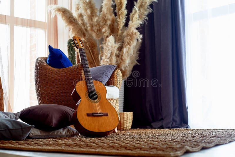 A chair and a rug made of rattan. Natural material. Pampas grass in a vase. Eco design.Guitar. Hipster Style