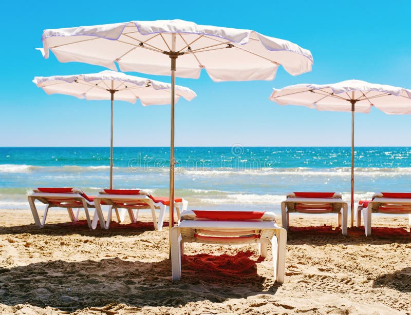 Chaises longues et parapluies dans une plage tranquille photos stock Chaises longues et parapluies dans une plage tranquille photos stock