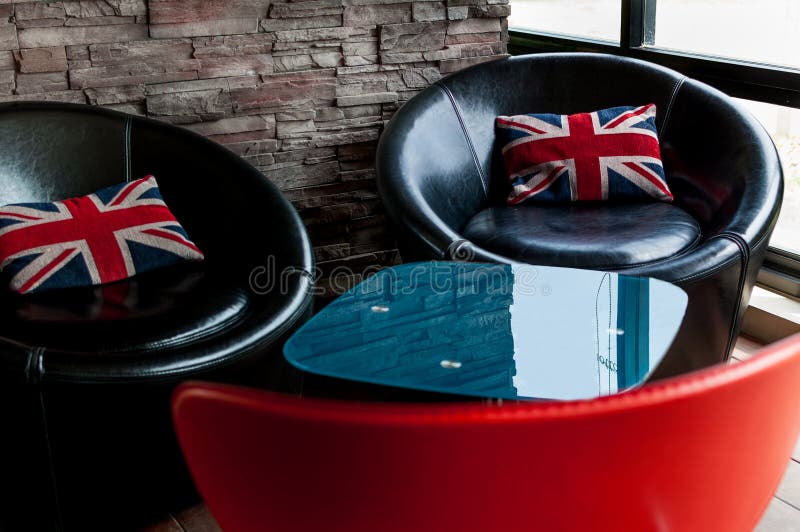 Black chairs with Union Jack pillows with bricks wall behind. Black chairs with Union Jack pillows with bricks wall behind