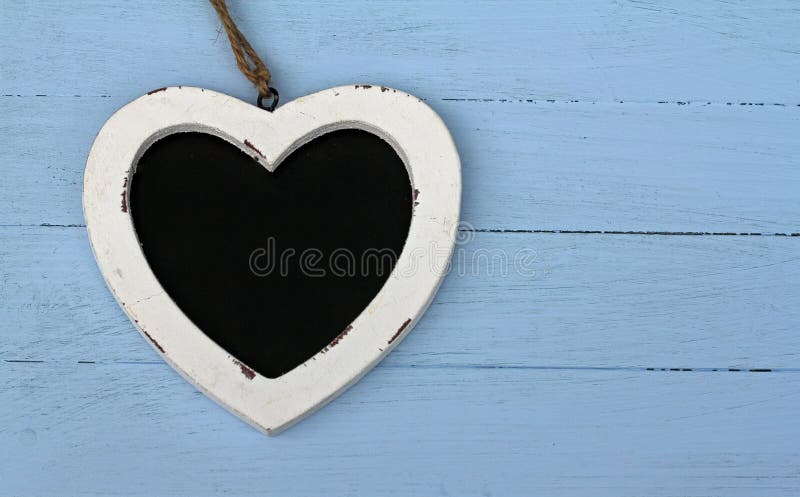 Heart shaped chalk board ,laying on blue painted floor boards. Heart shaped chalk board ,laying on blue painted floor boards