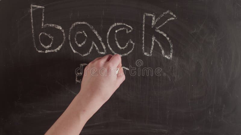 On the chalkboard is written back to school in letters. Chalked the phrase back to school on blackboard timelapse.