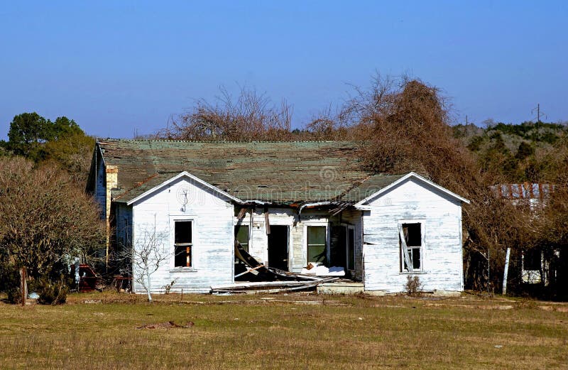 Damaged house with roof caving in and missing windows could illustrate storm or fire damage remodeling insurance needs etc. Damaged house with roof caving in and missing windows could illustrate storm or fire damage remodeling insurance needs etc