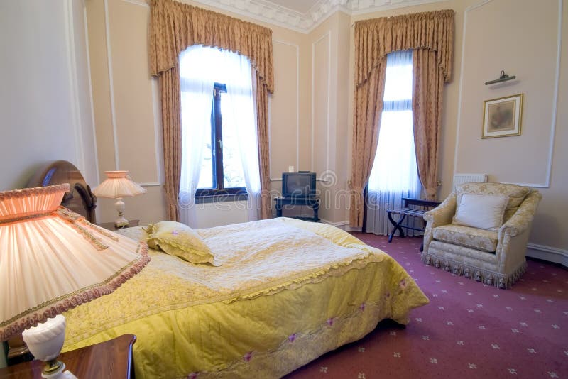 Interior of elegant hotel bedroom with a made bed and classic furniture. Interior of elegant hotel bedroom with a made bed and classic furniture.