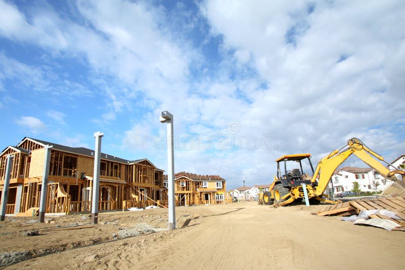 Wide angle view of new homes construction and also new houses already built with heavy machinery all under a beautiful sky. Wide angle view of new homes construction and also new houses already built with heavy machinery all under a beautiful sky.