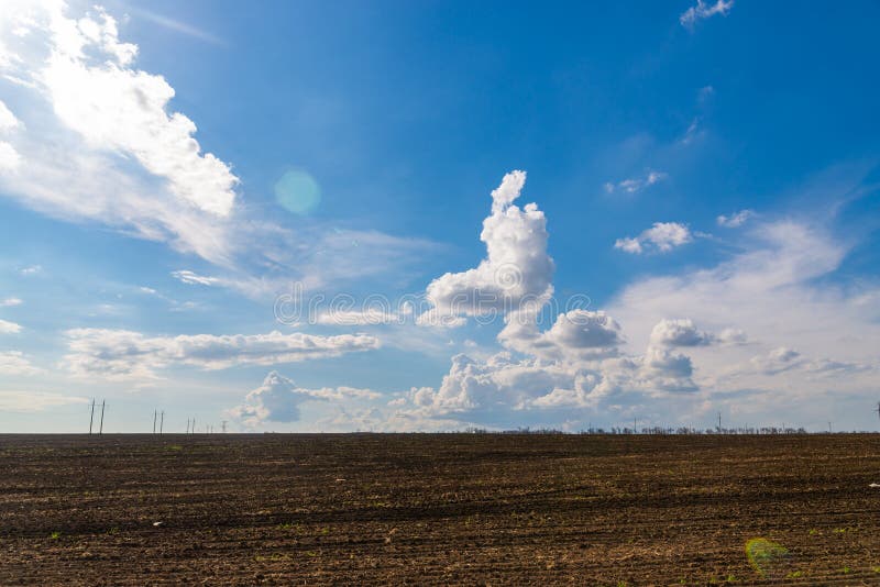 Champ noir d'agriculture et ciel bleu avec des nuages images libres de droits Champ noir d'agriculture et ciel bleu avec des nuages images libres de droits