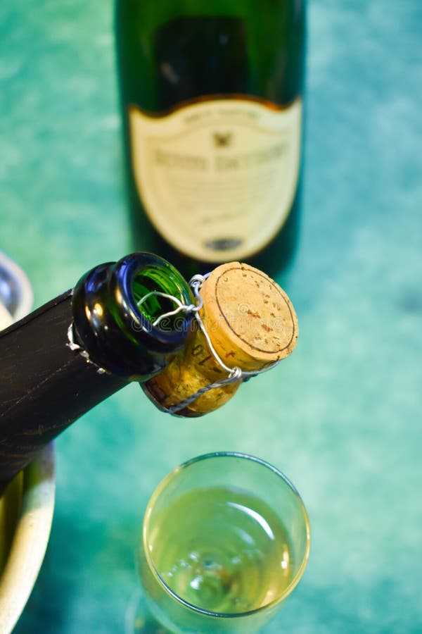 a champagne bottle in a cold bucket with ice and water, the cork holding from the mouth decorating the scene, a cup with sparking royalty free stock photography a champagne bottle in a cold bucket with ice and water, the cork holding from the mouth decorating the scene, a cup with sparking royalty free stock photography