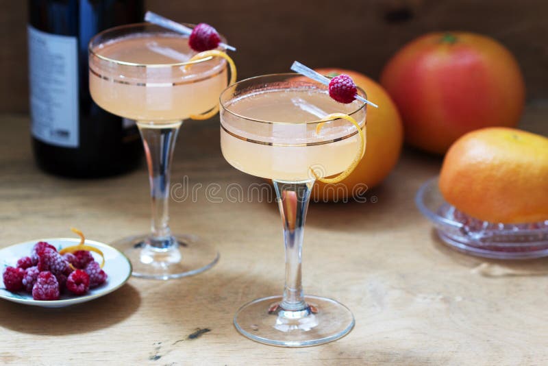 Champagne cocktail with grapefruit juice, garnished with zest and raspberries. Rustic style