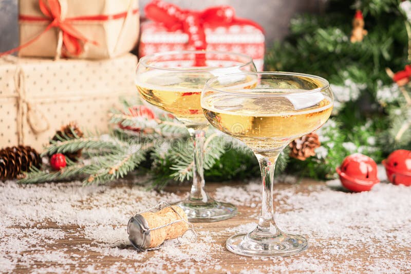 Champagne in elegant glass goblets festive Christmas table with gifts and a decorated Christmas tree. New Year concept.