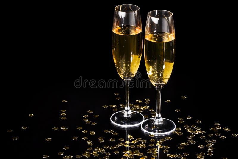 Flauti Champagne e stelle dorate su sfondo nero.