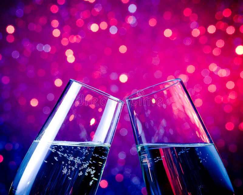 Champagne flutes with gold bubbles on blue tint light bokeh background