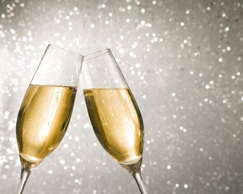 Champagne flutes with golden bubbles on silver light bokeh background