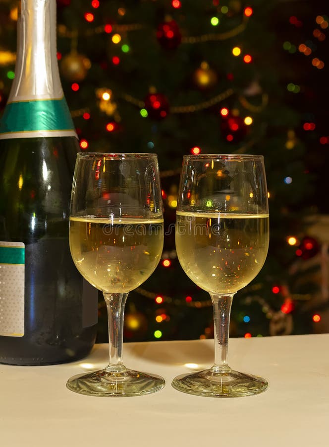 Glasses of champagne and wine bottle in front of bokeh Christmas tree. Glasses of champagne and wine bottle in front of bokeh Christmas tree.