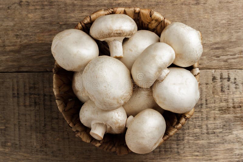 Champignons μανιταριών σε ένα ψάθινο καλάθι σε ένα ξύλινο υπόβαθρο στοκ εικόνα με δικαίωμα ελεύθερης χρήσης Champignons μανιταριών σε ένα ψάθινο καλάθι σε ένα ξύλινο υπόβαθρο στοκ εικόνα με δικαίωμα ελεύθερης χρήσης
