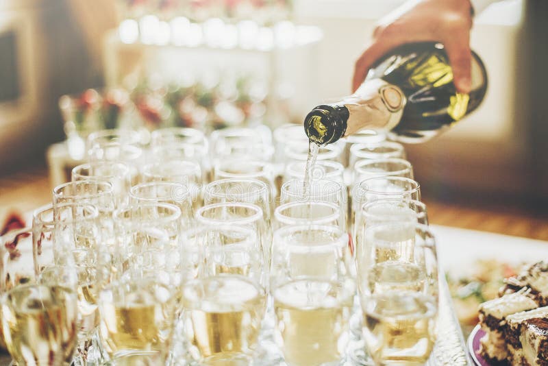 Champán de colada del camarero en vidrios elegantes en la boda de lujo con referencia a imágenes de archivo libres de regalías Champán de colada del camarero en vidrios elegantes en la boda de lujo con referencia a imágenes de archivo libres de regalías