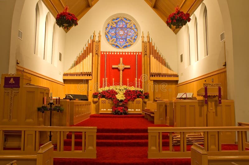 A view of the altar, pipe organ and the chancel of a modern Protestant church, decorated with red and white poinsettias for the Christmas season. A view of the altar, pipe organ and the chancel of a modern Protestant church, decorated with red and white poinsettias for the Christmas season.