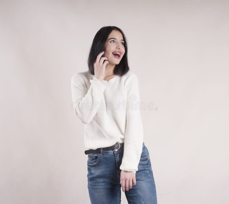 Chandail de port de jeans de belle fille de brune avec le studio de téléphone image libre de droits Chandail de port de jeans de belle fille de brune avec le studio de téléphone image libre de droits