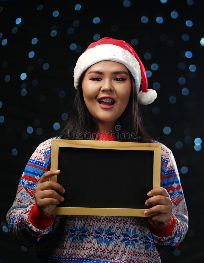 Chandail et Santa Hat Holding Small de port de Noël de fille asiatique image stock Chandail et Santa Hat Holding Small de port de Noël de fille asiatique image stock